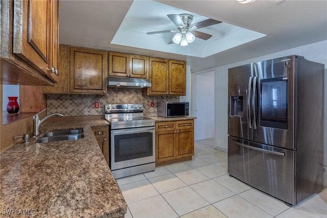 kitchen with decorative backsplash, appliances with stainless steel finishes, a raised ceiling, ceiling fan, and sink