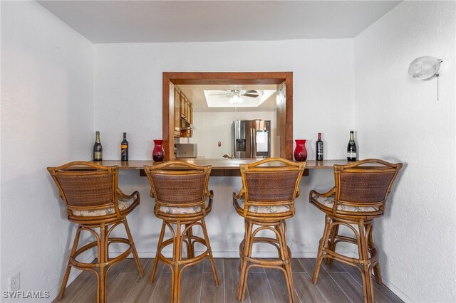 bar with stainless steel fridge, ceiling fan, and hardwood / wood-style flooring