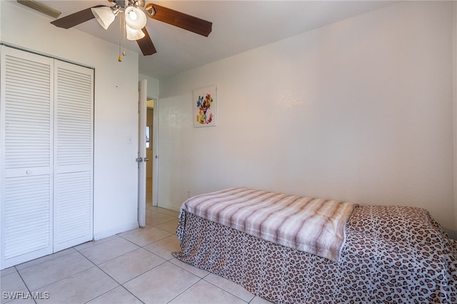 tiled bedroom featuring ceiling fan and a closet