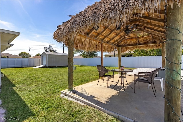 view of yard featuring a gazebo, ceiling fan, a storage unit, and a patio area