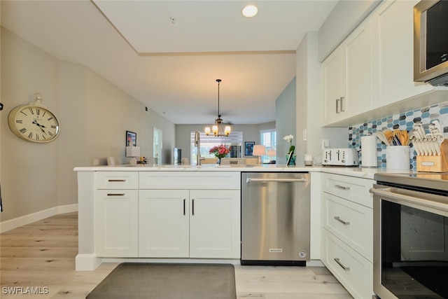 kitchen with a chandelier, white cabinetry, appliances with stainless steel finishes, and light hardwood / wood-style flooring