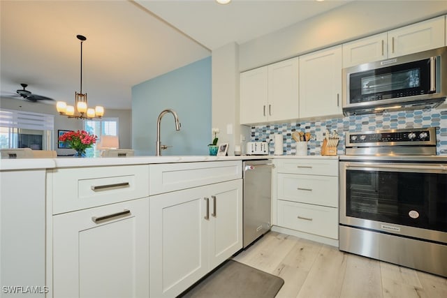 kitchen featuring pendant lighting, light hardwood / wood-style flooring, appliances with stainless steel finishes, tasteful backsplash, and white cabinetry