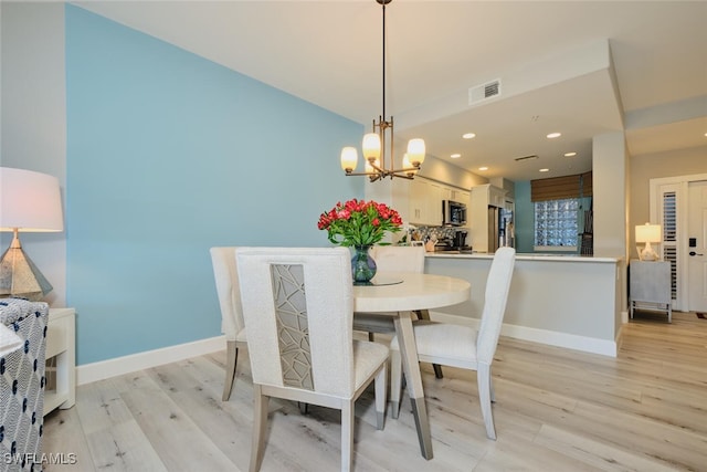 dining space with a chandelier and light hardwood / wood-style flooring