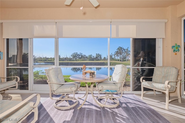 sunroom / solarium featuring ceiling fan and a water view