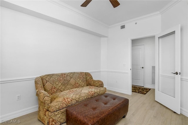 living area with crown molding, ceiling fan, and light hardwood / wood-style floors