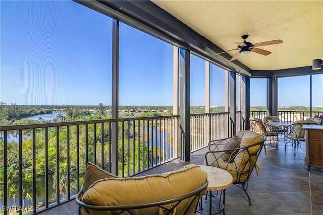 sunroom / solarium with ceiling fan and a water view