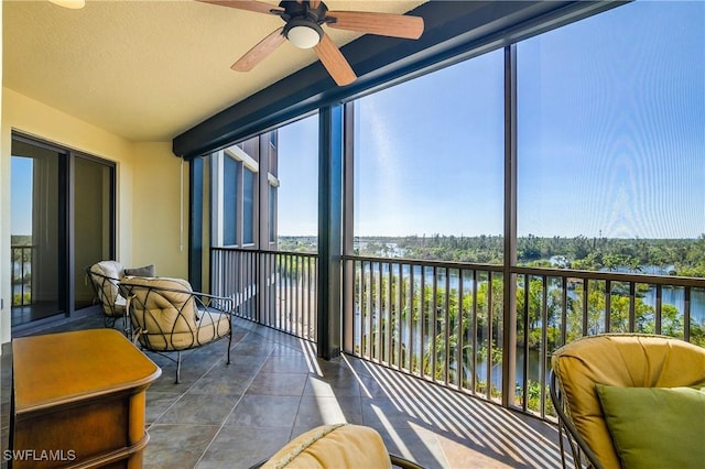 sunroom / solarium with plenty of natural light, ceiling fan, and a water view