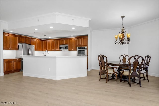 kitchen featuring appliances with stainless steel finishes, light wood-type flooring, crown molding, an inviting chandelier, and hanging light fixtures