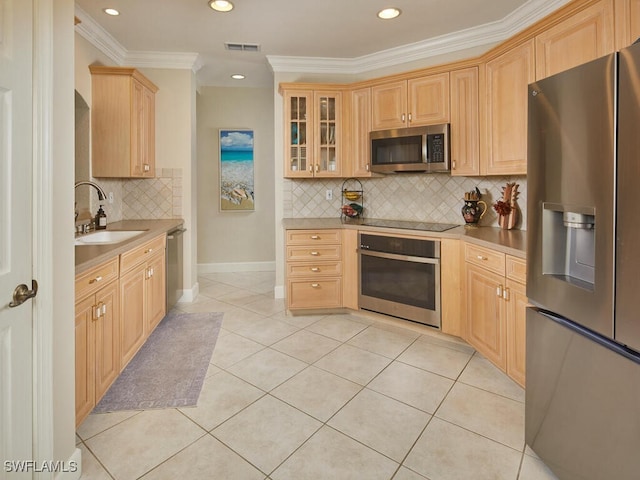 kitchen featuring stainless steel appliances, light countertops, visible vents, glass insert cabinets, and a sink