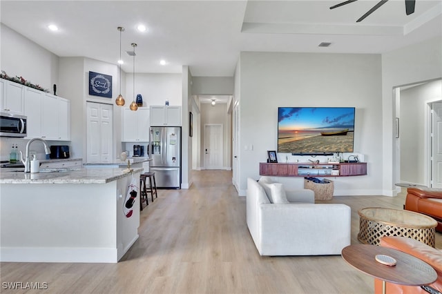 kitchen featuring white cabinetry, pendant lighting, light stone counters, and appliances with stainless steel finishes