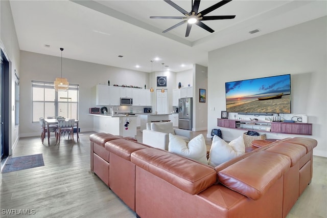 living room featuring ceiling fan, light hardwood / wood-style flooring, and sink