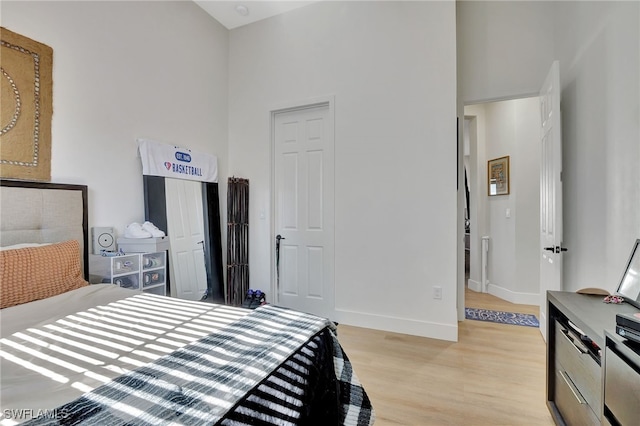 bedroom featuring light wood-type flooring and a towering ceiling