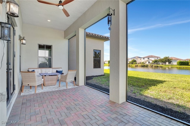 sunroom featuring ceiling fan and a water view