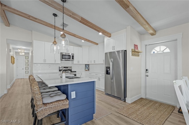 kitchen with white cabinetry, a breakfast bar, hanging light fixtures, and appliances with stainless steel finishes