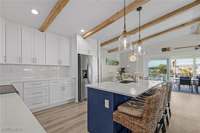 kitchen featuring white cabinets, lofted ceiling with beams, stainless steel refrigerator with ice dispenser, hanging light fixtures, and tasteful backsplash