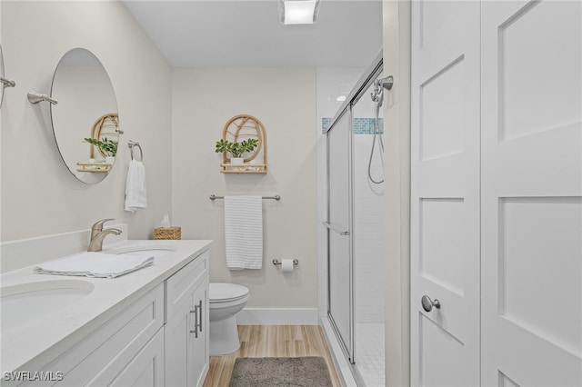 bathroom with hardwood / wood-style floors, vanity, toilet, and a shower with shower door