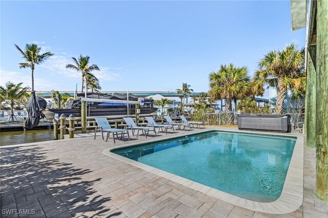 view of swimming pool with a boat dock, a water view, and a patio