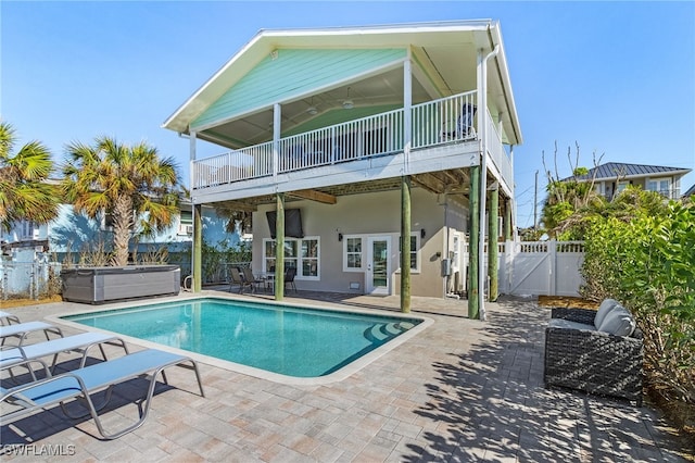 rear view of property featuring a patio area and a pool with hot tub