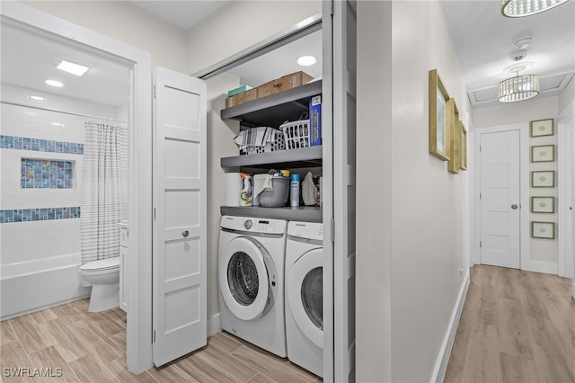 clothes washing area featuring light wood-type flooring and washer and clothes dryer