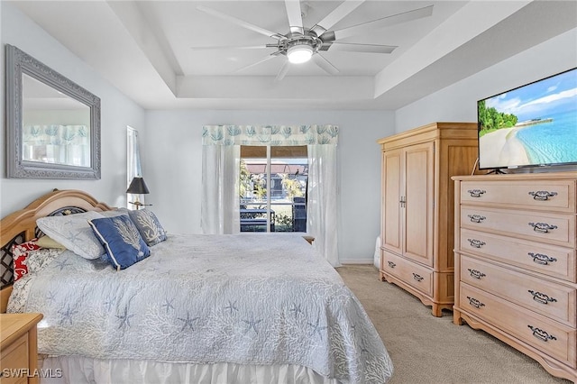 carpeted bedroom featuring ceiling fan, a raised ceiling, and access to outside