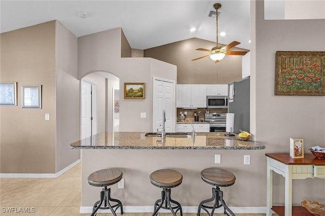 kitchen with dark stone counters, sink, appliances with stainless steel finishes, white cabinetry, and kitchen peninsula