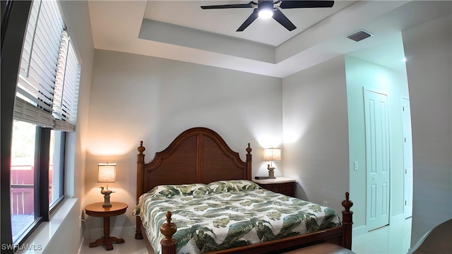 bedroom with a tray ceiling, ceiling fan, and a closet