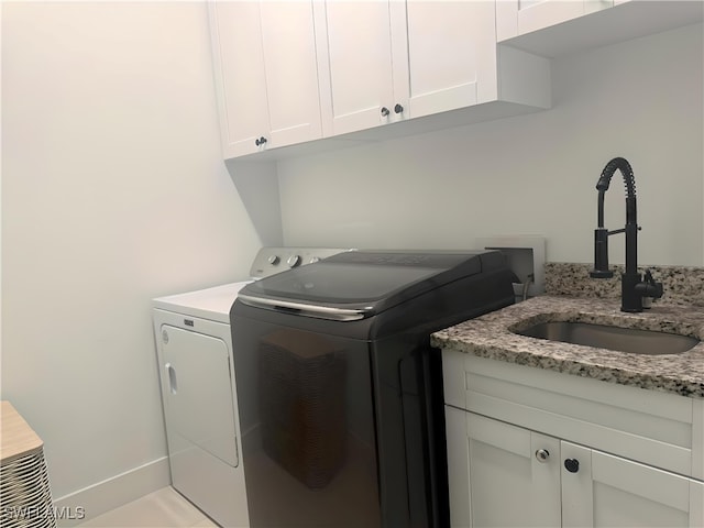 laundry area with cabinets, light tile patterned floors, washer and clothes dryer, and sink