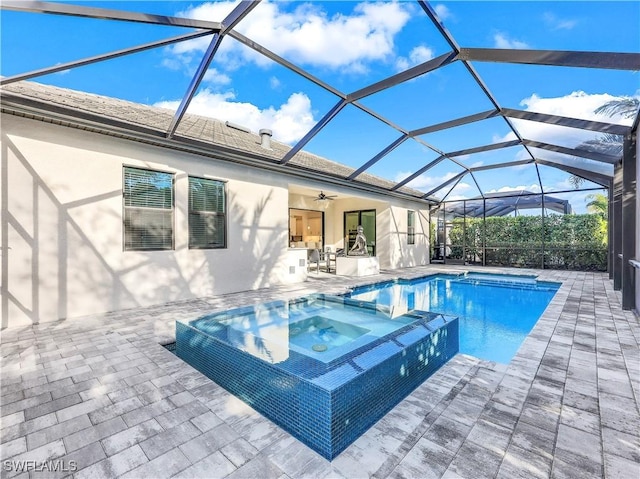 view of swimming pool featuring glass enclosure, an in ground hot tub, ceiling fan, and a patio