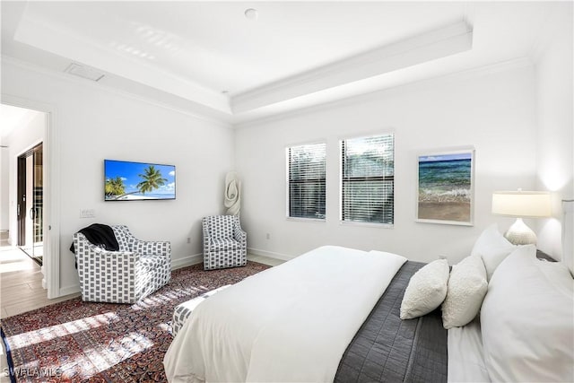 bedroom featuring access to outside, a tray ceiling, hardwood / wood-style flooring, and ornamental molding