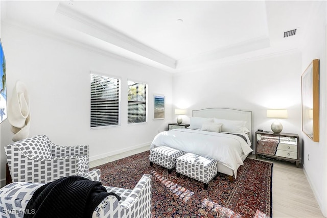 bedroom featuring ornamental molding, a tray ceiling, and light hardwood / wood-style floors