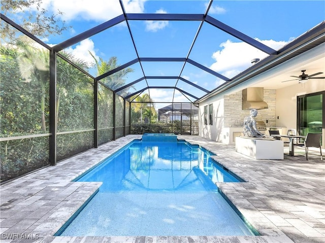 view of pool with area for grilling, a patio, glass enclosure, and ceiling fan