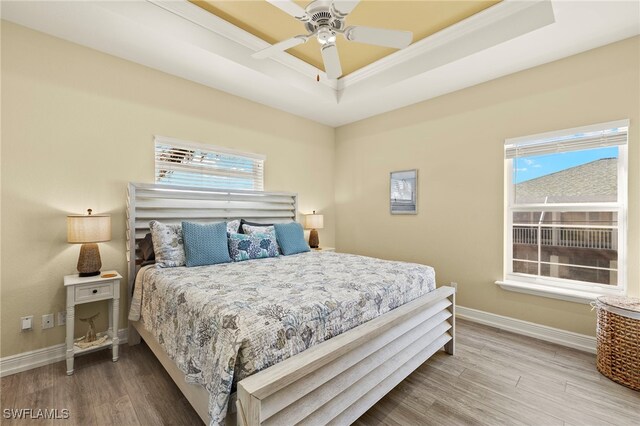 bedroom featuring hardwood / wood-style floors, ceiling fan, and multiple windows