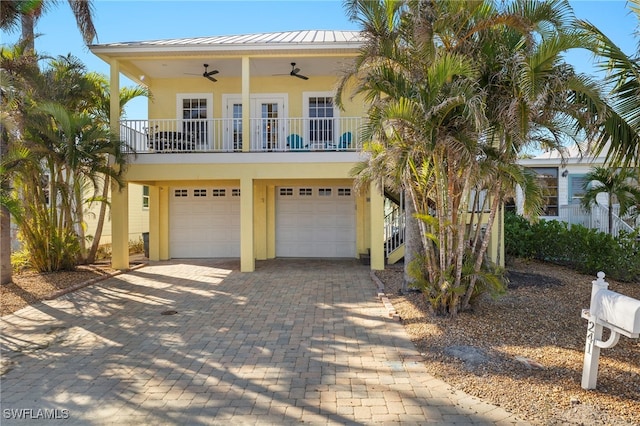 241 Pearl St, Fort Myers Beach, FL 33931 - coastal inspired home with stucco siding, metal roof, driveway, an attached garage, and a ceiling fan