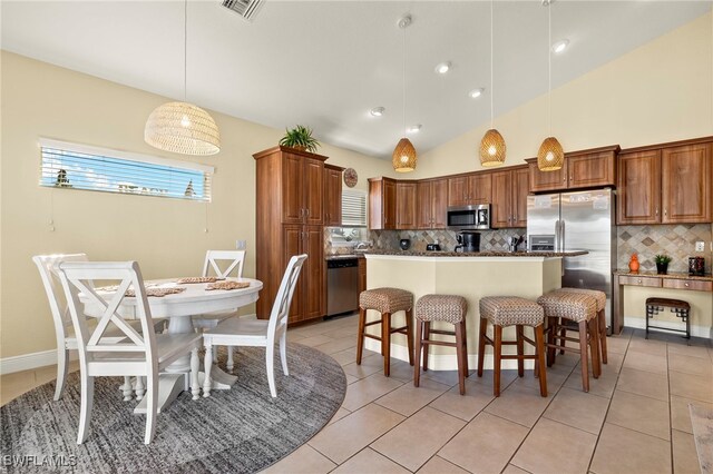 kitchen with decorative light fixtures, a center island, stainless steel appliances, and a breakfast bar area