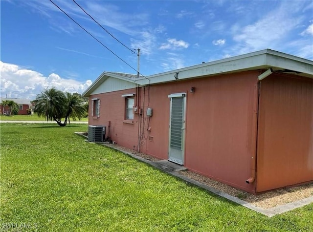 view of side of property featuring a yard and central AC