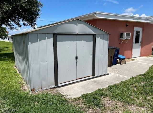 view of outdoor structure featuring a yard and a wall mounted AC