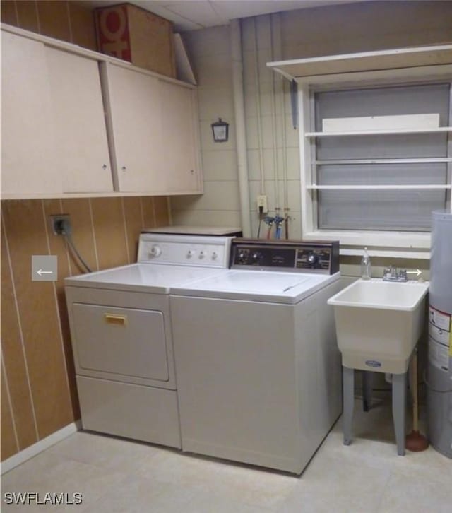 laundry area with washer and dryer, cabinets, sink, and gas water heater