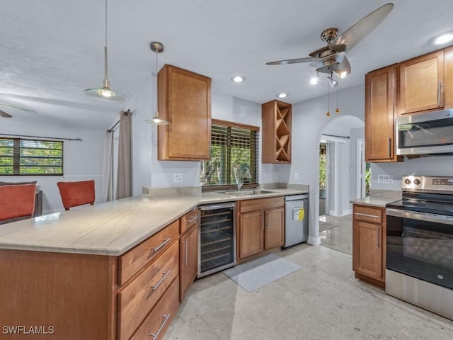 kitchen with appliances with stainless steel finishes, ceiling fan, beverage cooler, sink, and hanging light fixtures