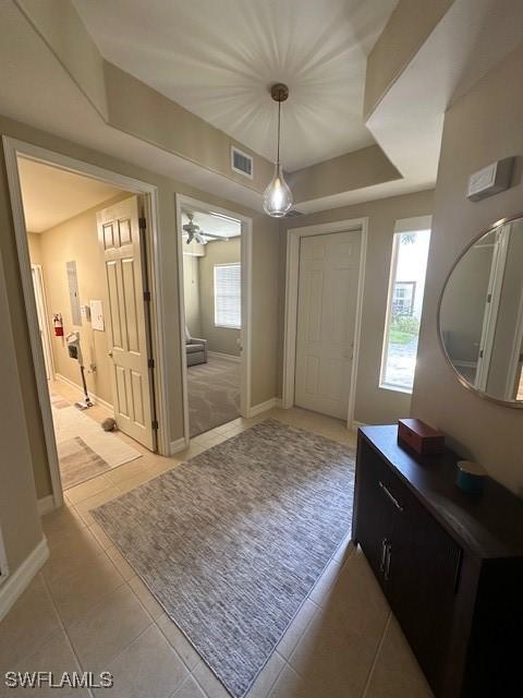 interior space featuring tile patterned flooring, a tray ceiling, and ceiling fan