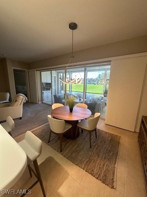 dining area featuring light tile patterned floors and an inviting chandelier