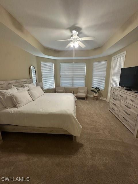 unfurnished bedroom with a raised ceiling, dark carpet, and ceiling fan