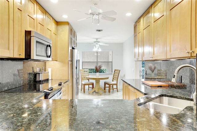 kitchen with tasteful backsplash, dark stone countertops, sink, and stainless steel appliances