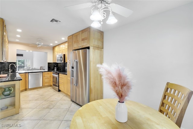 kitchen featuring tasteful backsplash, ceiling fan, light brown cabinetry, and stainless steel appliances