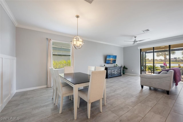 dining area featuring ceiling fan with notable chandelier, baseboards, visible vents, and crown molding