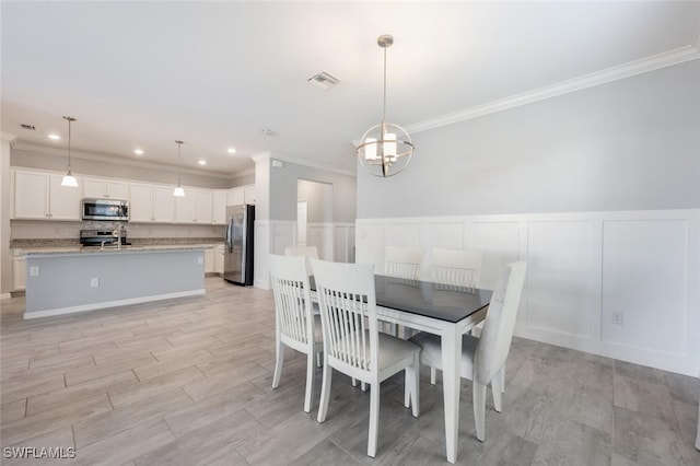 dining room with visible vents, a decorative wall, a notable chandelier, and wainscoting