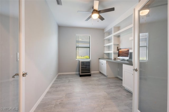 office space featuring beverage cooler, visible vents, baseboards, and built in study area