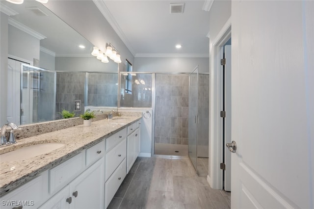 bathroom featuring ornamental molding, a stall shower, visible vents, and a sink