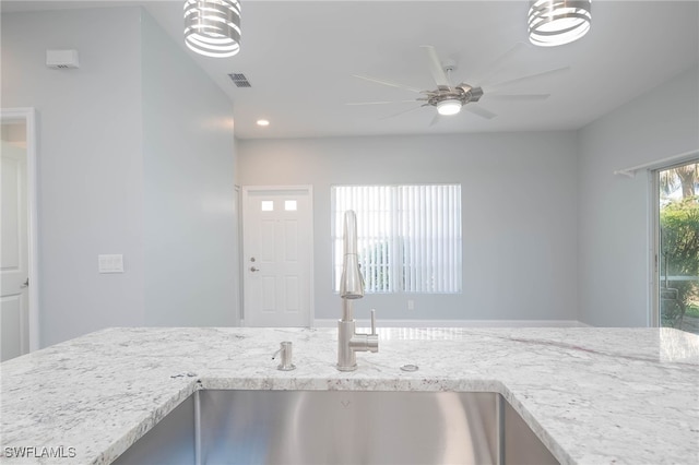 interior space featuring light stone countertops, ceiling fan, and sink