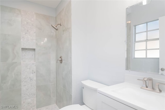 bathroom with vanity, toilet, and a tile shower