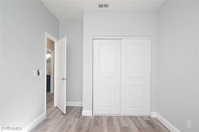 unfurnished bedroom with a closet and light wood-type flooring